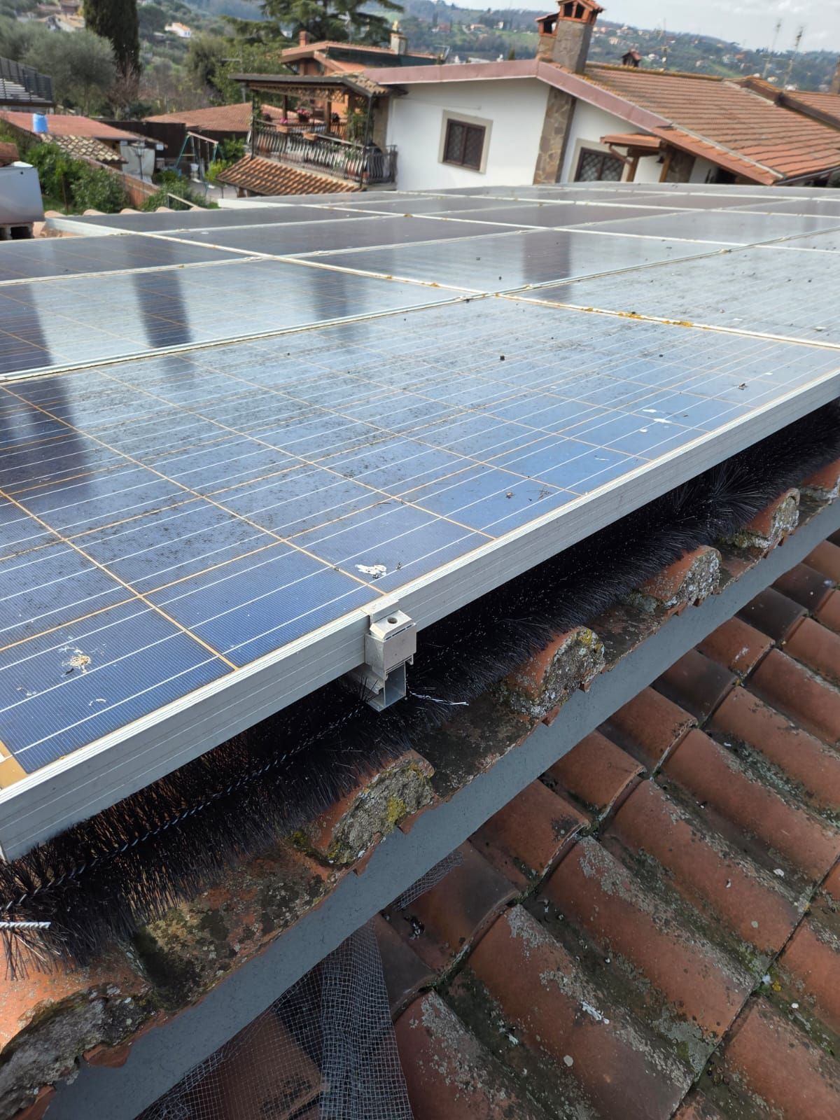 Pannelli solari installati sul tetto in tegole di terracotta di un edificio residenziale.