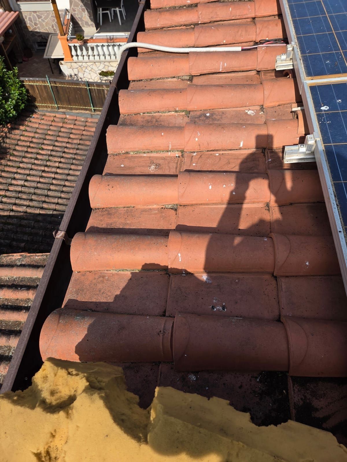 Vista delle tegole marroni, della grondaia e del bordo del pannello solare.
