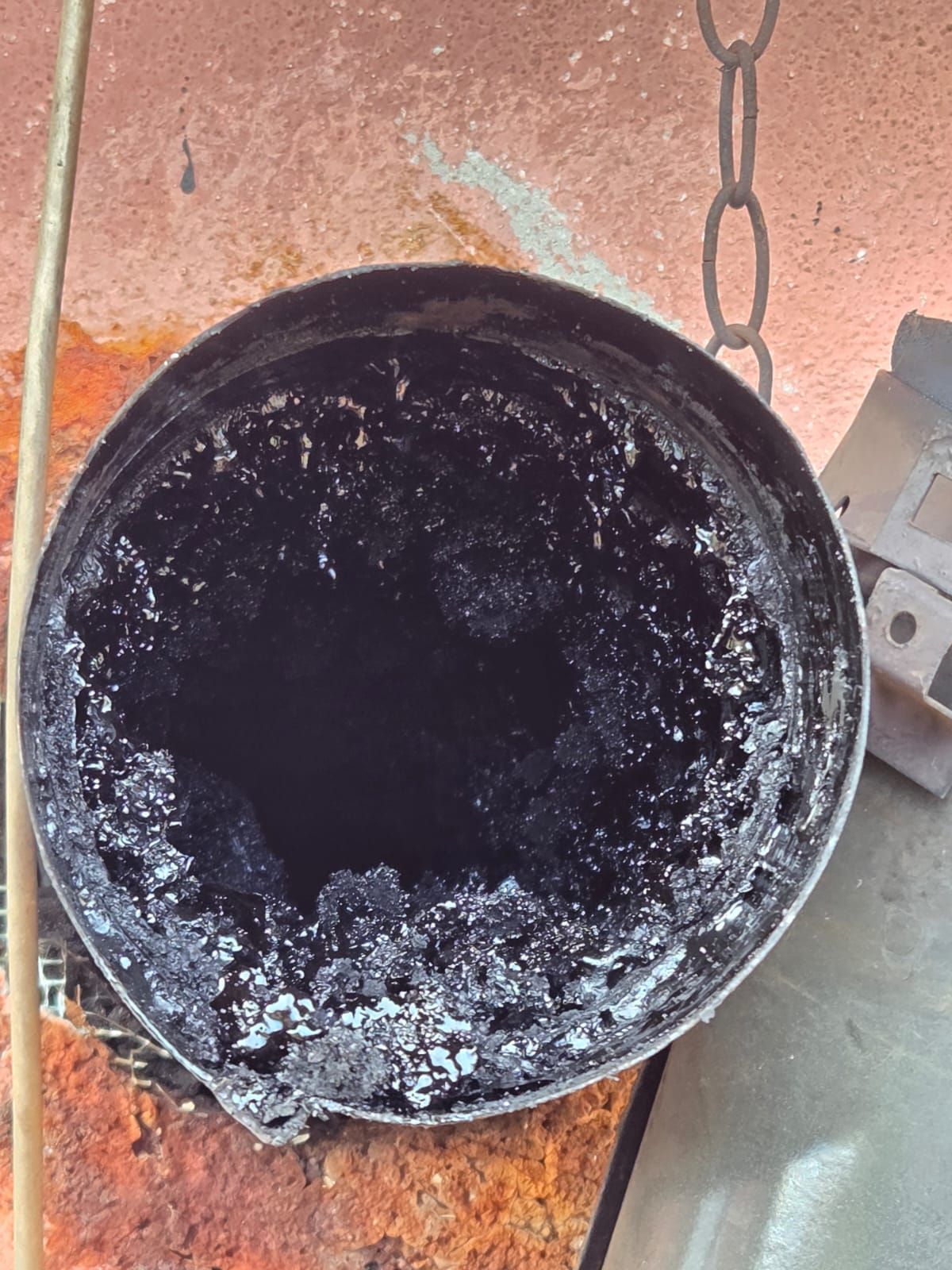 All'interno di un contenitore metallico ricoperto da un residuo nero con del materiale cristallizzato e lucido; montatura arrugginita.