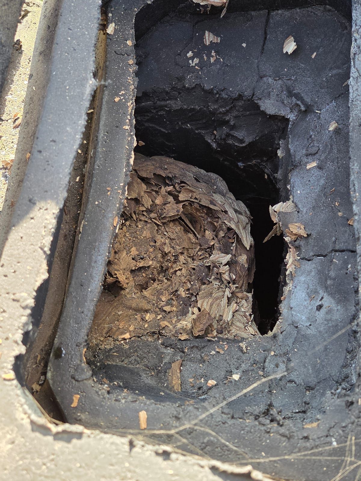 Un buco rettangolare con un grosso ammasso di detriti all'interno di una cornice scura, probabilmente di asfalto.