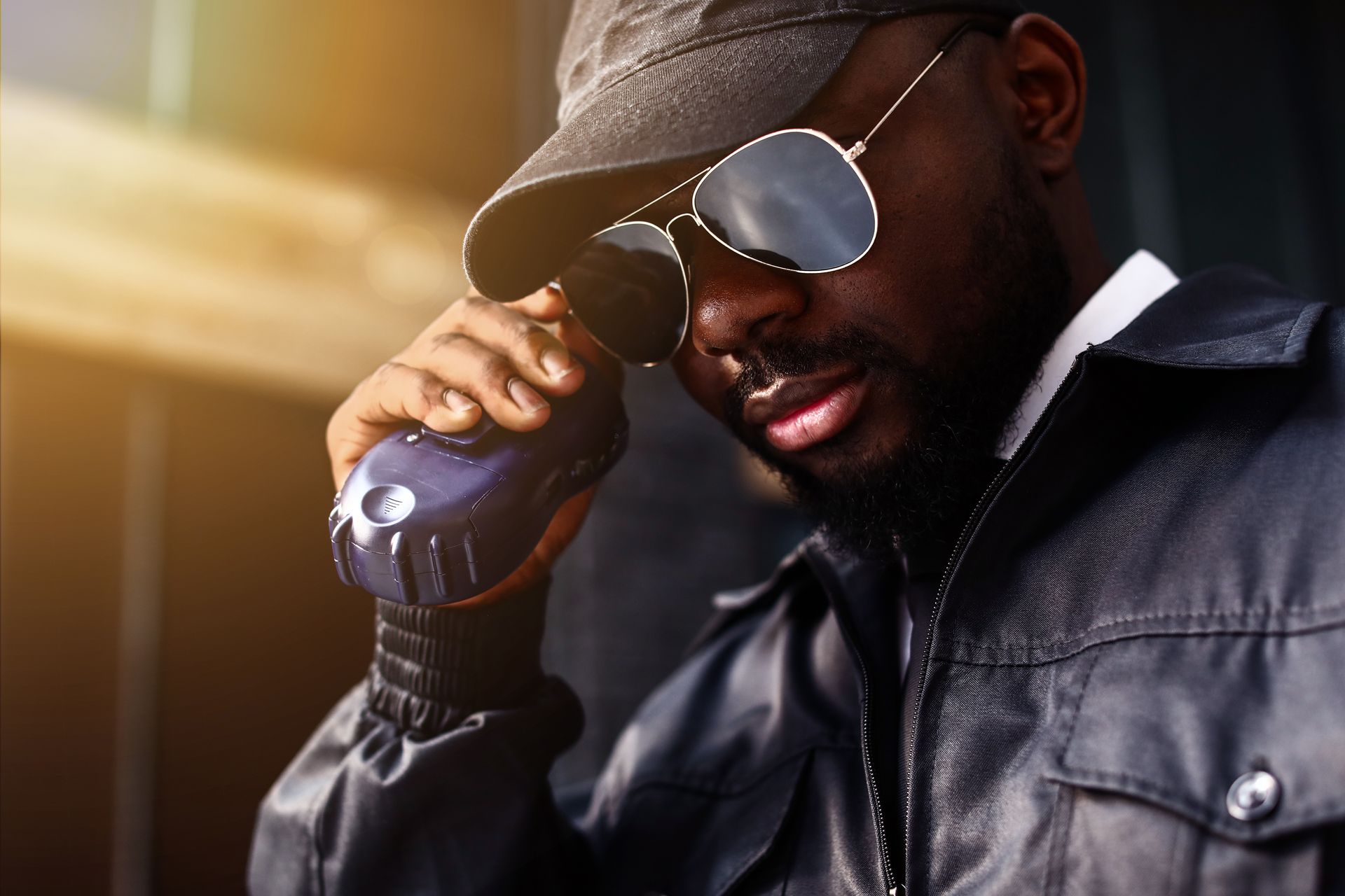 A man wearing sunglasses and a hat is talking on a cell phone.