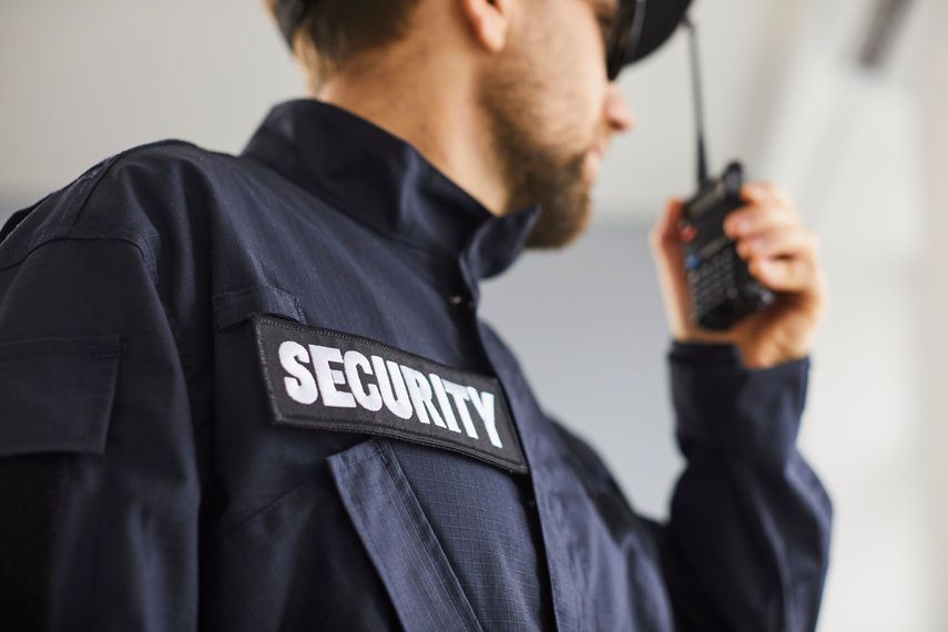 A security guard is talking on a walkie talkie.