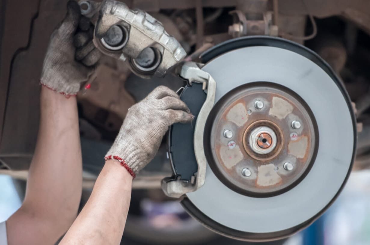 A Person Is Fixing A Brake Pad On A Car — Uncle Tonys Auto And Mechanical In Currumbin Waters, QLD