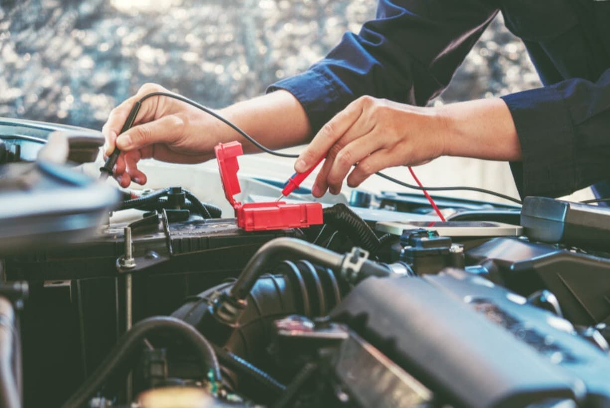 A Man Is Working On A Car Engine With A Voltmeter — Uncle Tonys Auto And Mechanical In Currumbin Waters, QLD