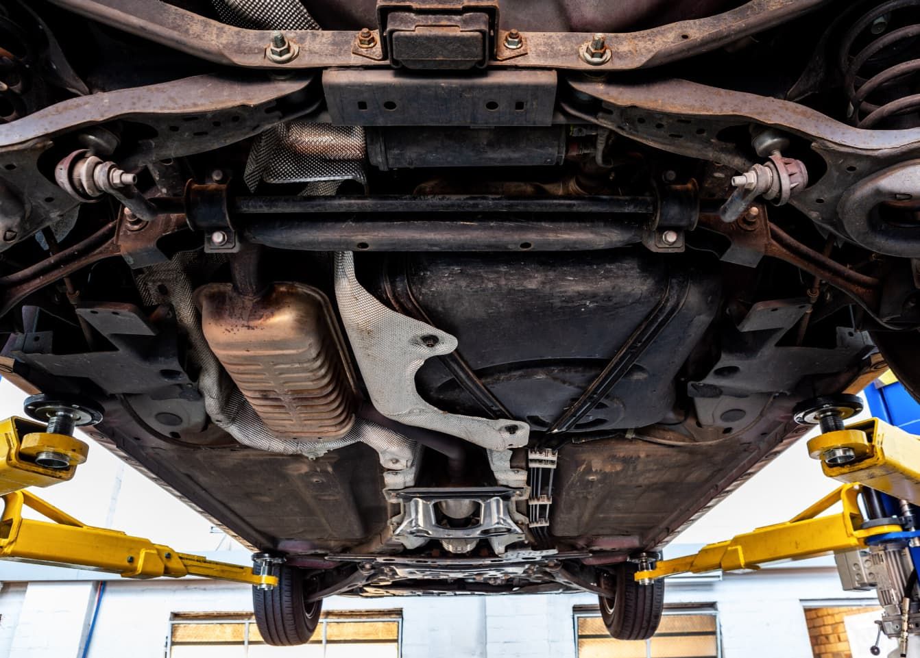 The Underside Of A Car On A Lift In A Garage — Uncle Tonys Auto And Mechanical In Currumbin Waters, QLD