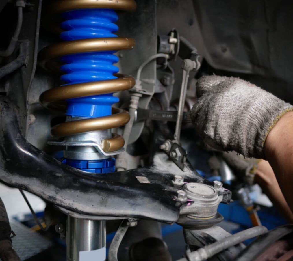A Person Is Working On A Blue Shock Absorber On A Car — Uncle Tonys Auto And Mechanical In Currumbin Waters, QLD