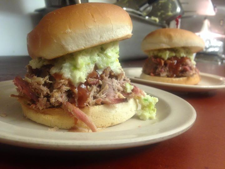 Pulled pork sandwich with coleslaw and BBQ sauce, topped with a bun. 