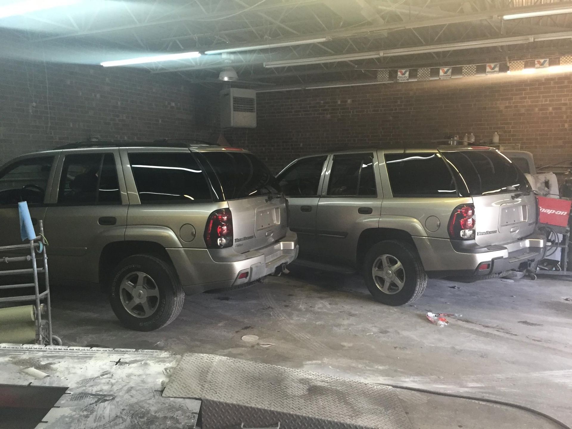 Two silver SUVs parked closely in a garage.