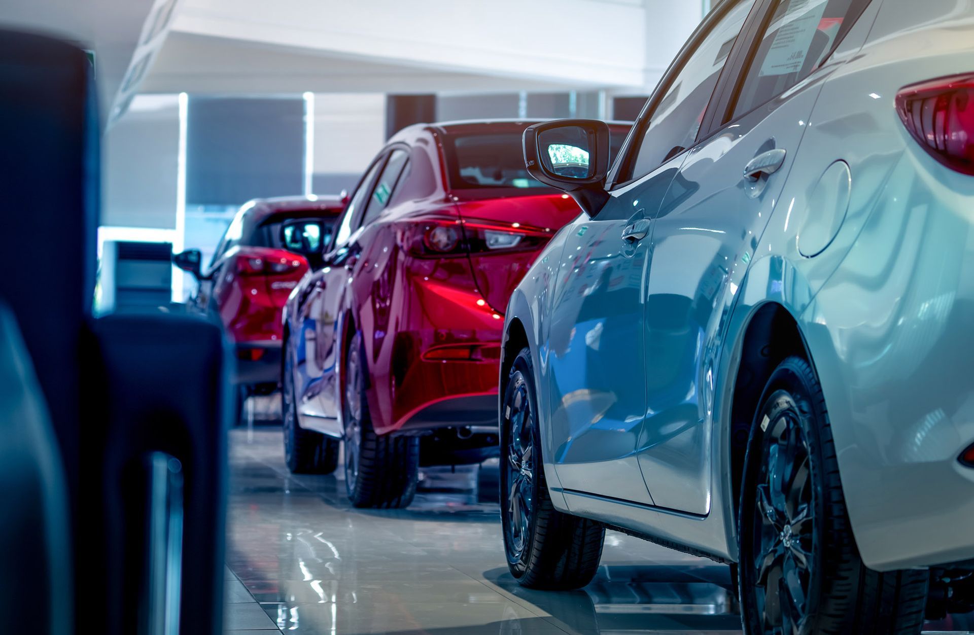 Cars in a showroom, white and red, lined up.
