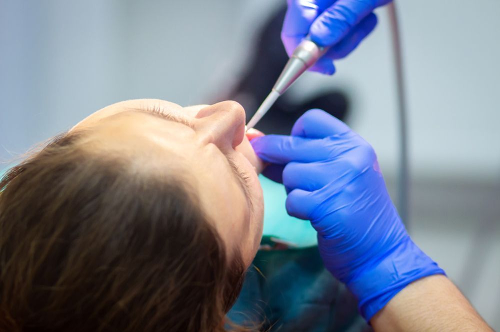 Dentist and assistant examining patient's teeth in a dental office.