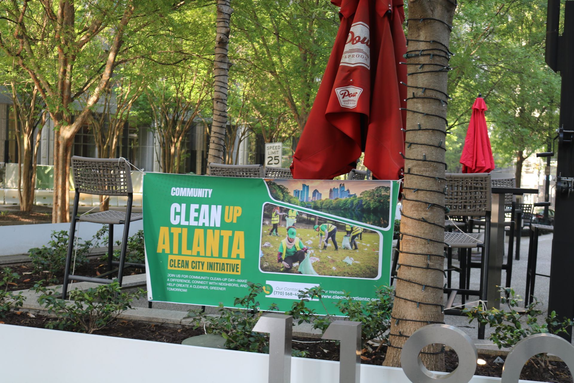 Green “Clean Atlanta” banner with trees, red umbrellas, and an outdoor patio area in the background