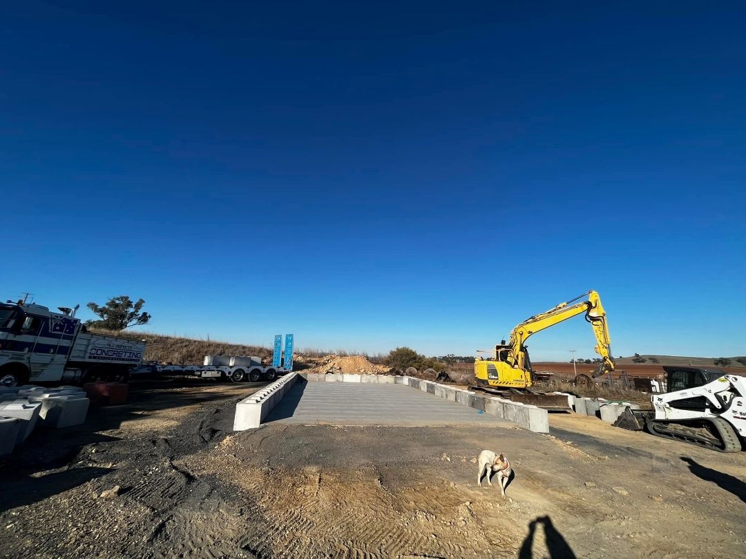 A Dirt Road Next to a Yellow Excavator — All Aspects Concreting & Earthworks Pty Ltd in Dubbo, NSW