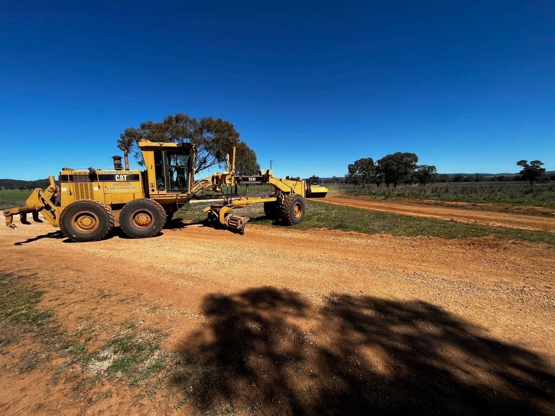 A Yellow Tractor is Parked on the Side of a Dirt Road — All Aspects Concreting & Earthworks Pty Ltd in Dubbo, NSW