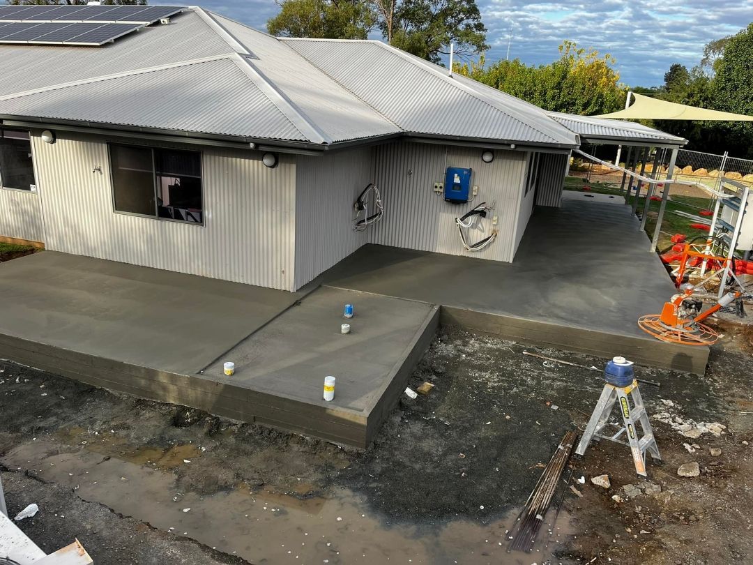 A House is Being Built With a Concrete Driveway in Front of It — All Aspects Concreting & Earthworks Pty Ltd in Warren, NSW