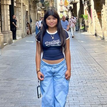 A girl wearing a brooklyn shirt is walking down a street