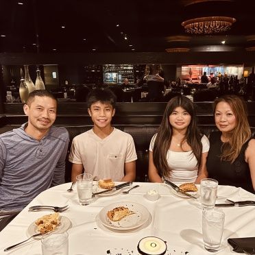 A group of people are sitting at a table with plates of food.