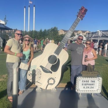 A group of people standing in front of a large guitar that says cage the elephant