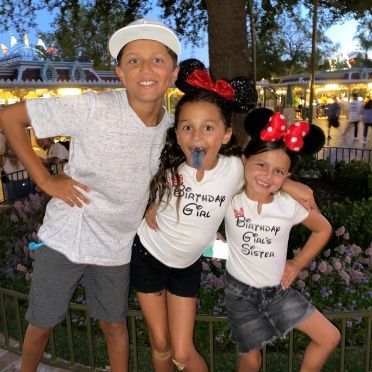 A boy and two girls pose for a picture with one girl wearing a shirt that says birthday girl
