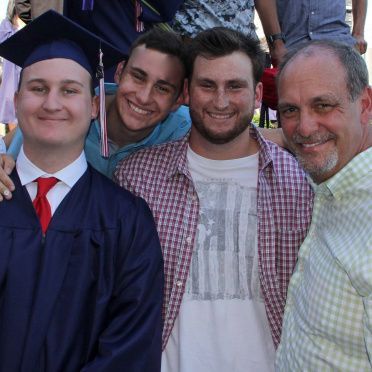 A group of men posing for a picture with one wearing an american flag shirt