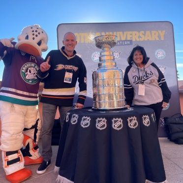 A group of ducks mascots standing next to a trophy