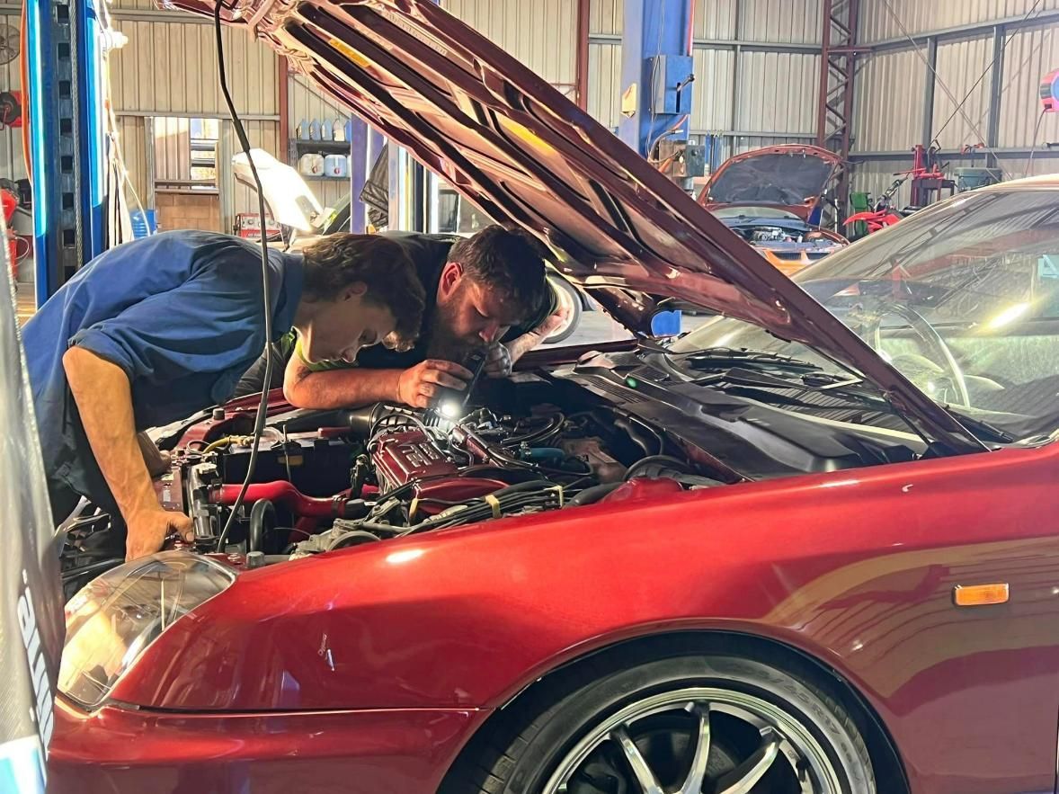 Two Men Are Working On A Red Car In A Garage — Chrisp Performance in Emerald, QLD
