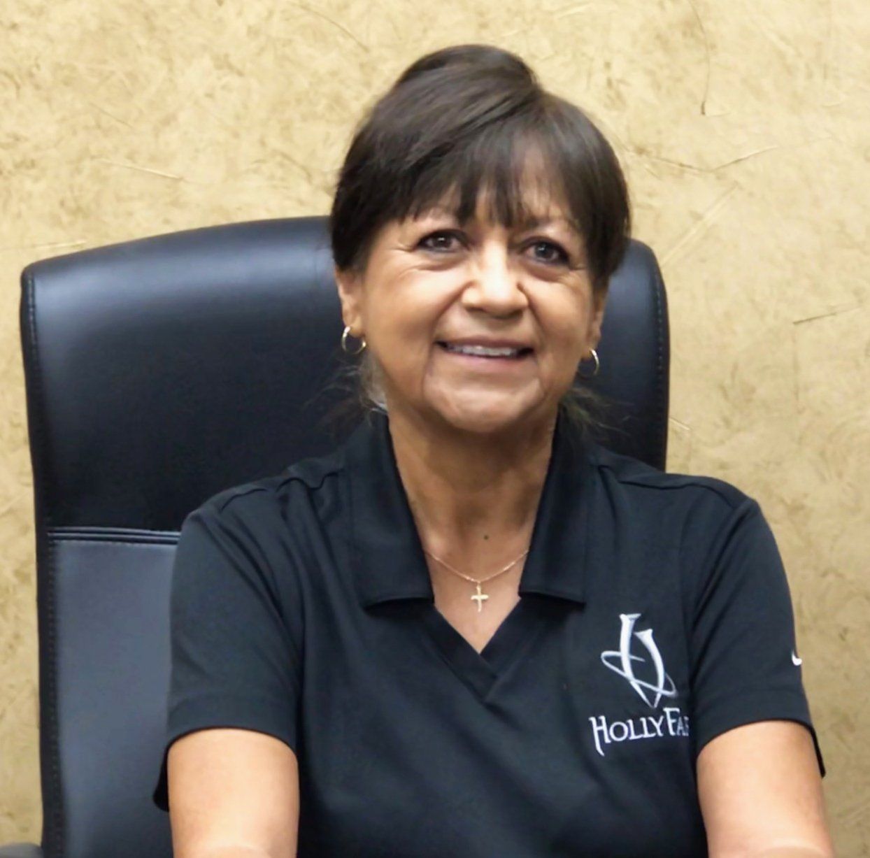 Woman in a black polo shirt smiling at the camera.