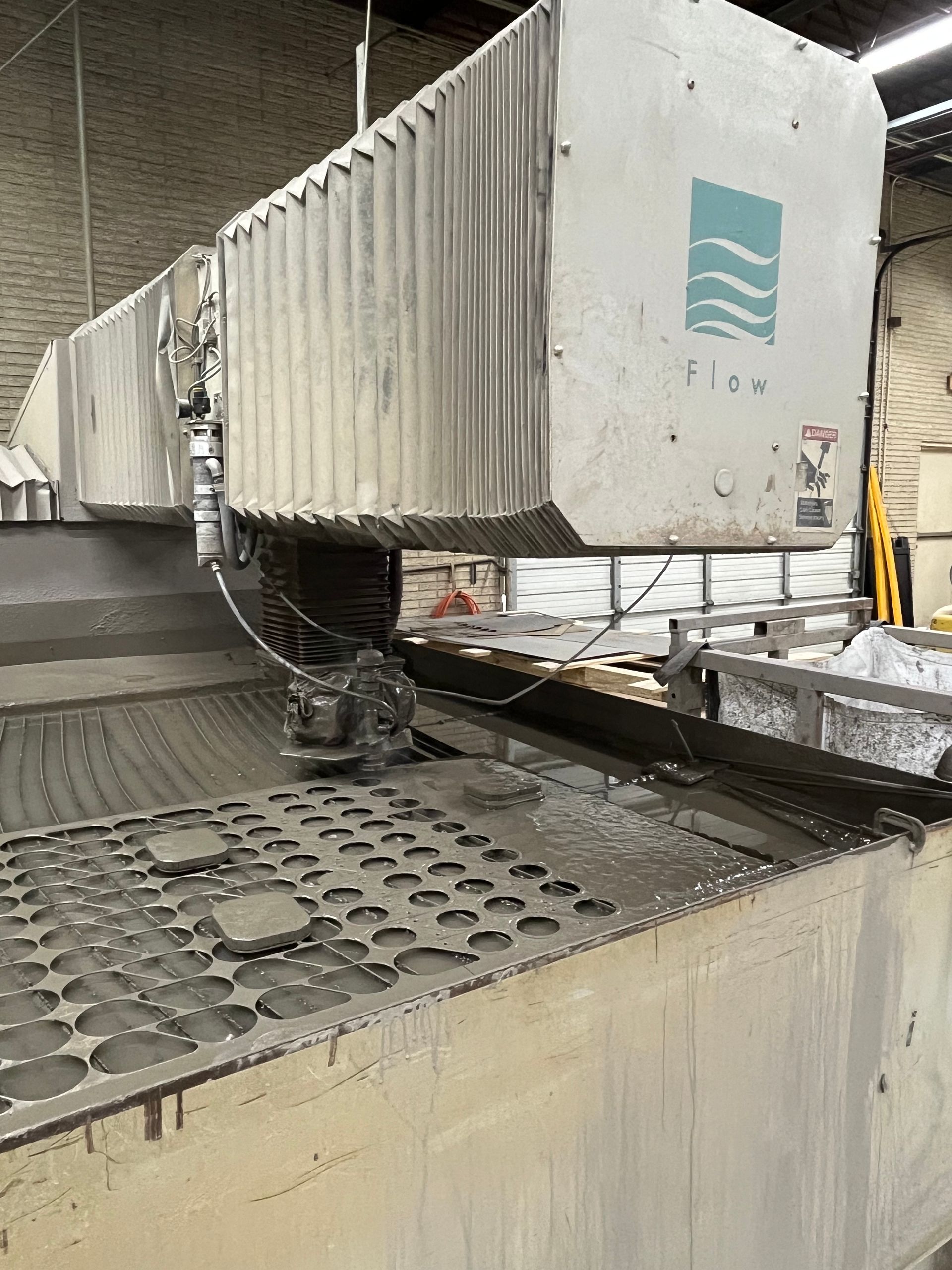 A waterjet cutting machine in a workshop. The machine is cutting a metal sheet.