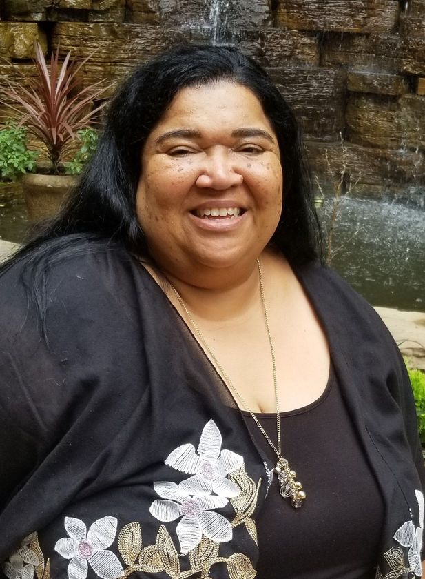 a woman with long black hair is smiling in front of a waterfall .