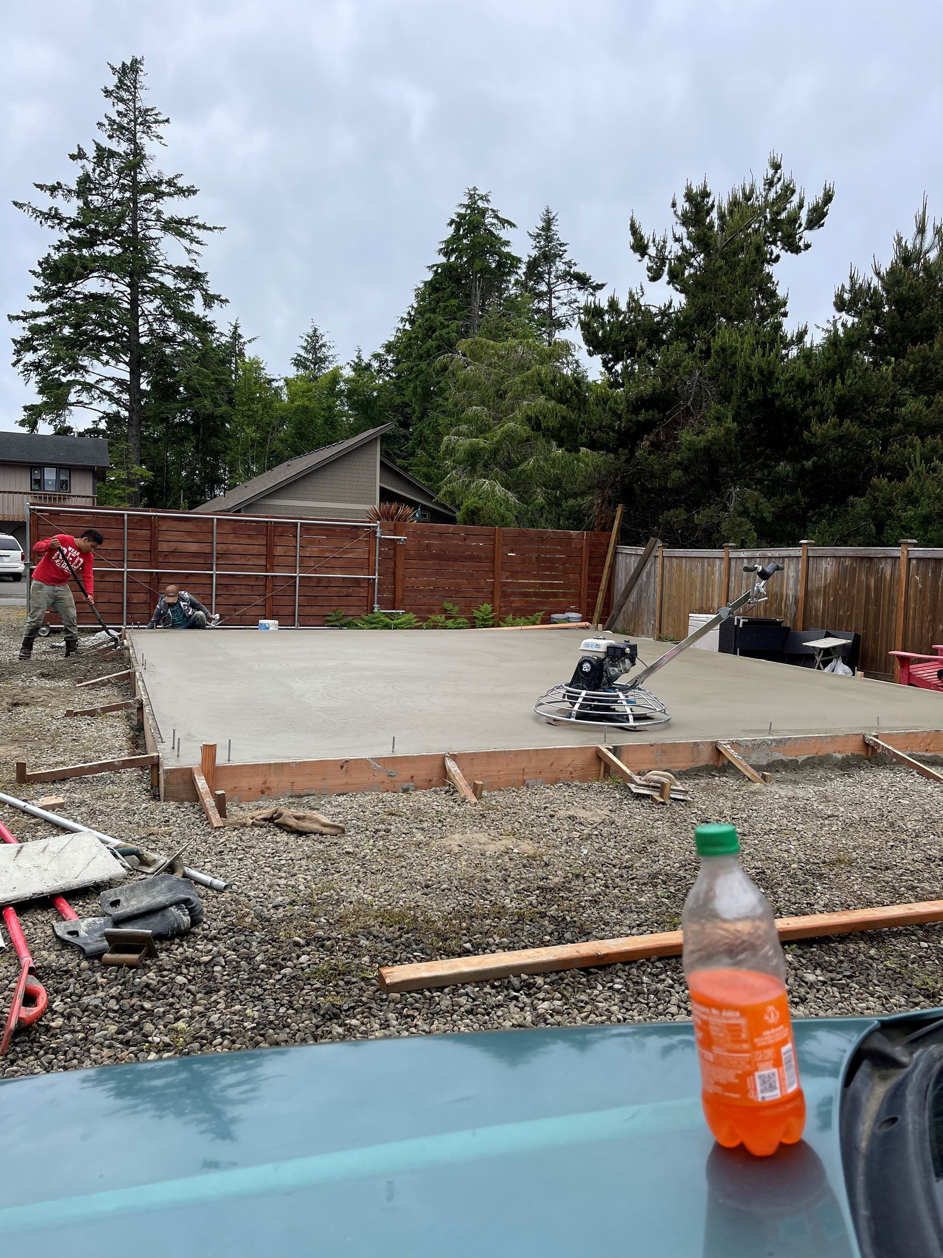 A bottle of orange soda is sitting on a table in front of a construction site.