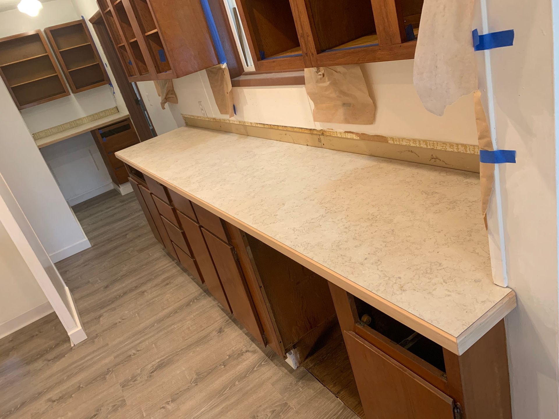 A kitchen with a long counter top and wooden cabinets.