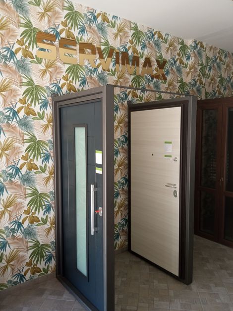 Un carrello elevatore Toyota arancione e un transpallet elettrico arancione più piccolo, entrambi parcheggiati in un corridoio di stoccaggio di un magazzino industriale.