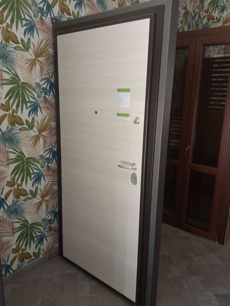 Durante una riunione in ufficio, una persona con un maglione rosso gesticola mentre parla con un uomo che indossa un maglione scuro e gli occhiali.