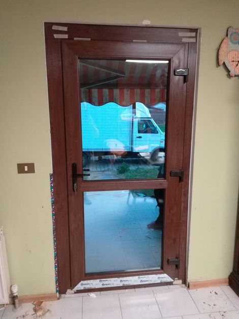 Un carrello elevatore Toyota arancione e un transpallet elettrico arancione più piccolo, entrambi parcheggiati in un corridoio di stoccaggio di un magazzino industriale.