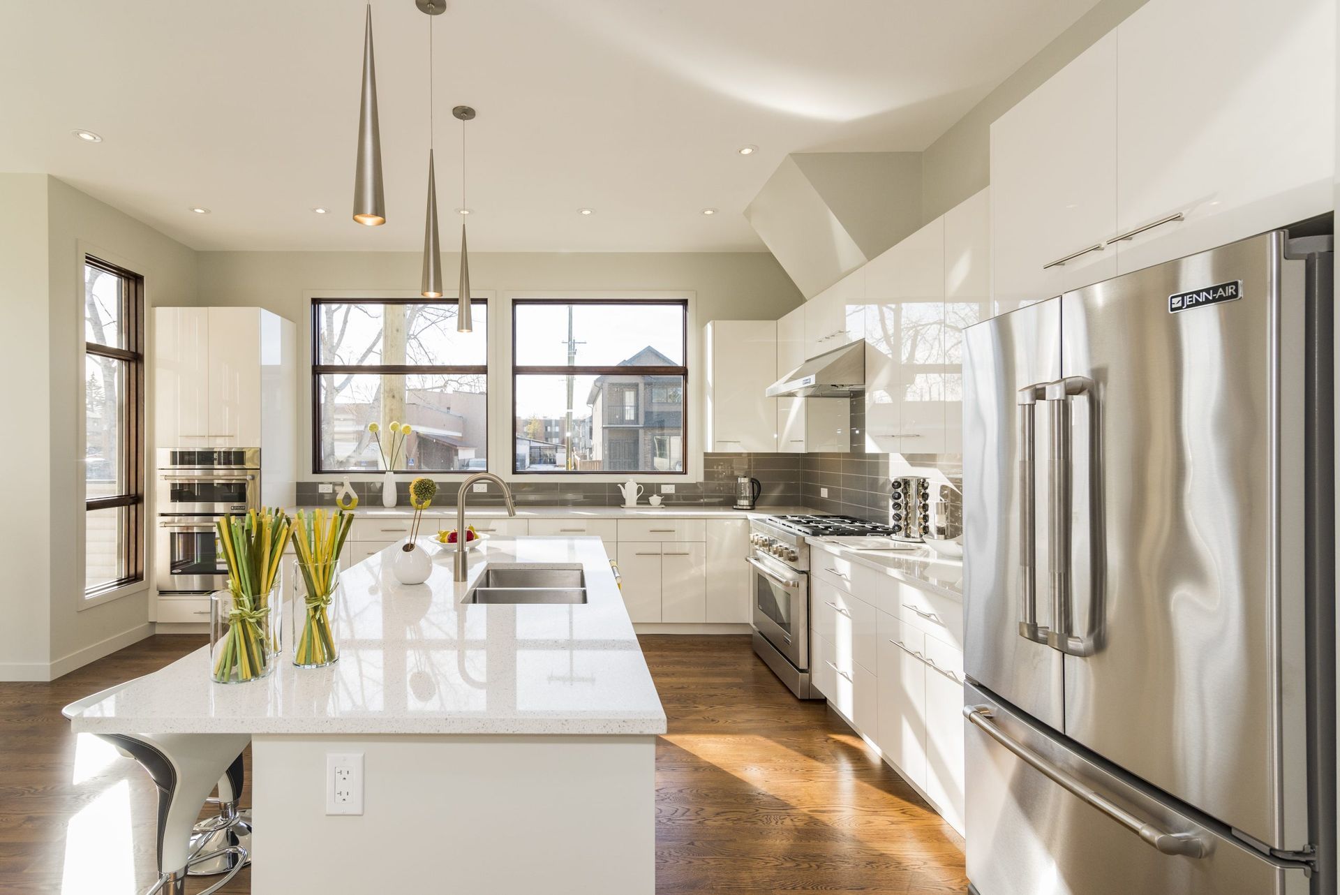 Bright modern kitchen with white cabinets, island, and stainless steel appliances