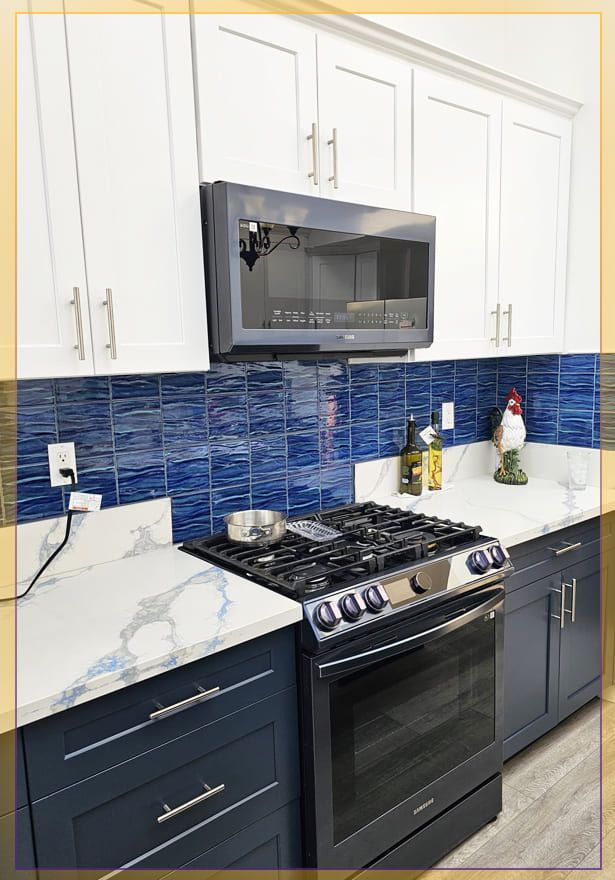 Modern kitchen with white cabinets, blue tile backsplash, black stove, and marble countertops