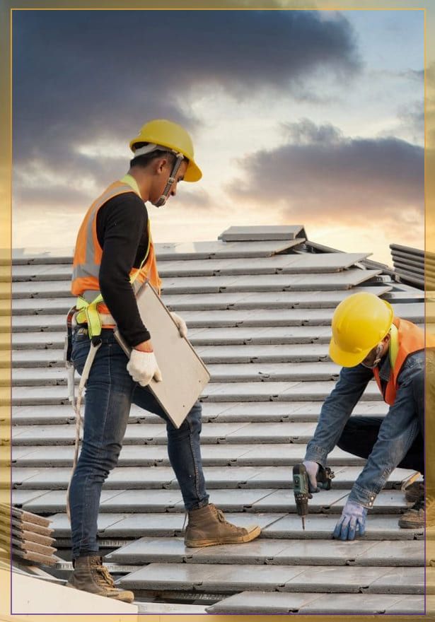 Two construction workers in yellow hard hats inspect a rooftop under a cloudy sky.