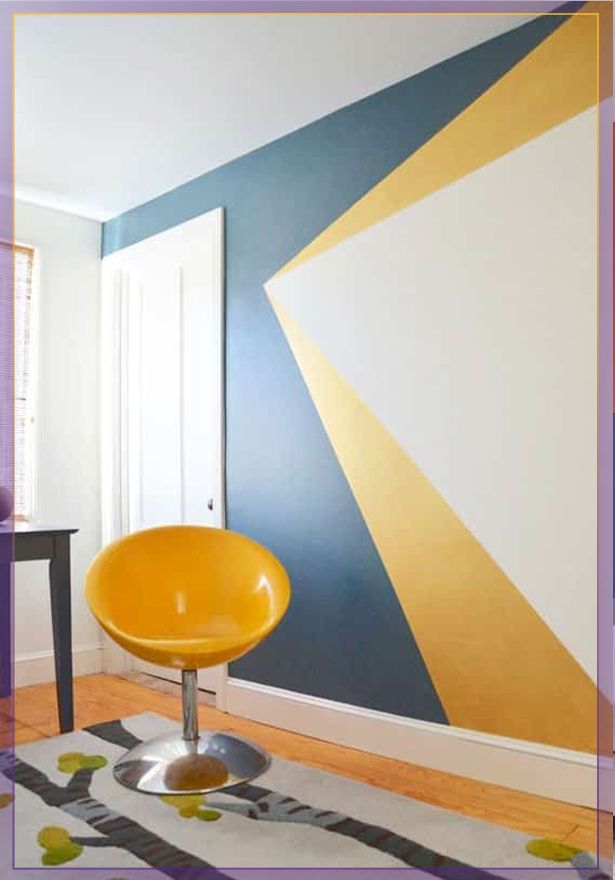 Modern room with gray and yellow geometric wall art, white door, and orange chair on a patterned rug