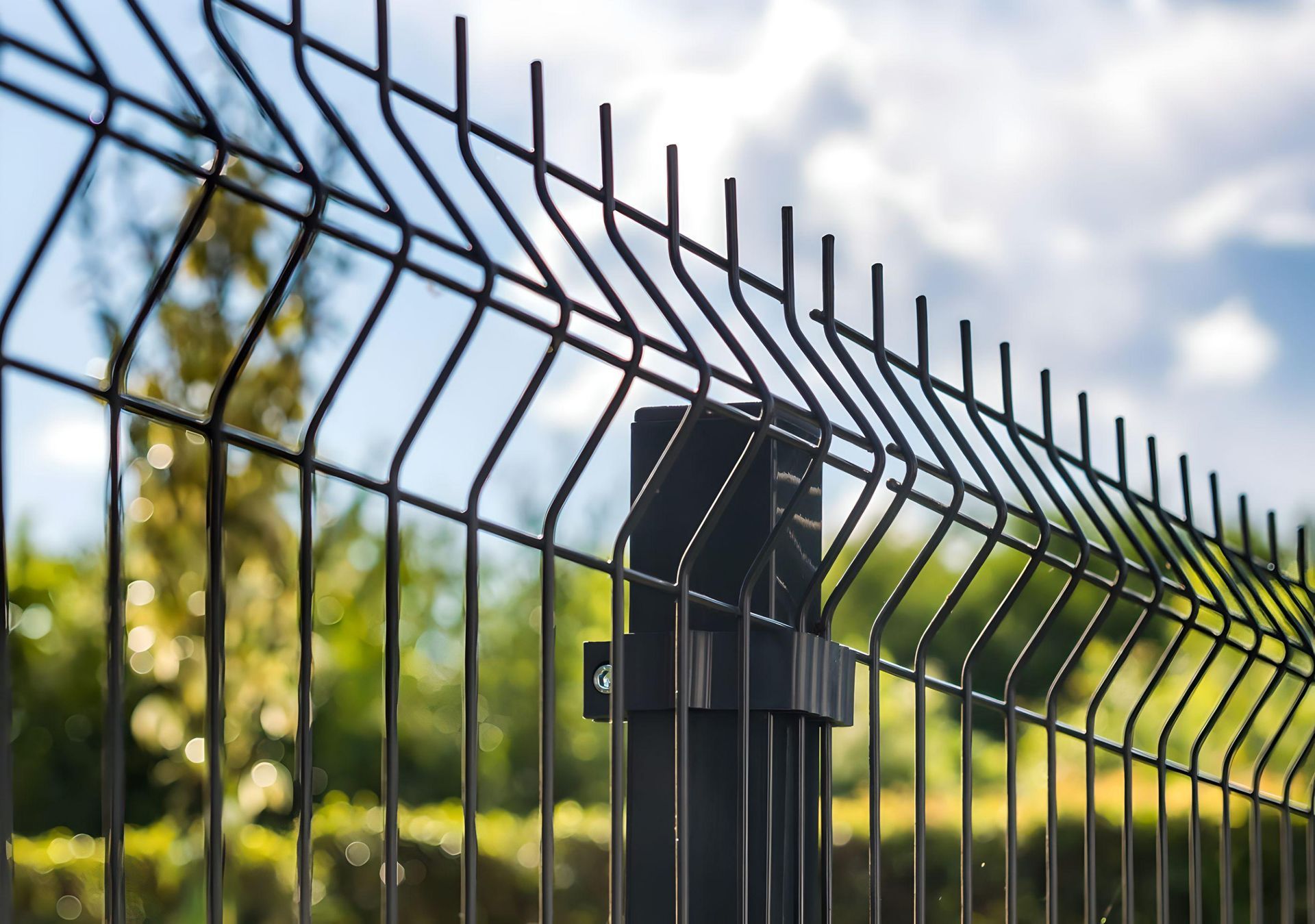 A close up of a wire fence with trees in the background.
