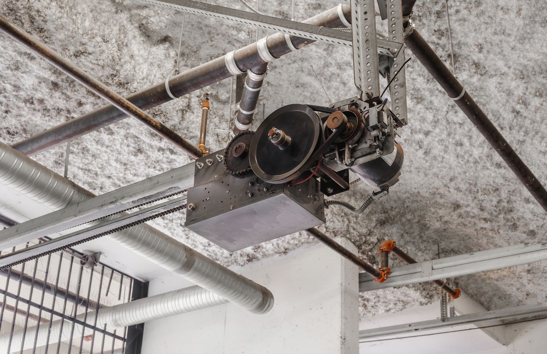 A garage door opener is hanging from the ceiling of a building.