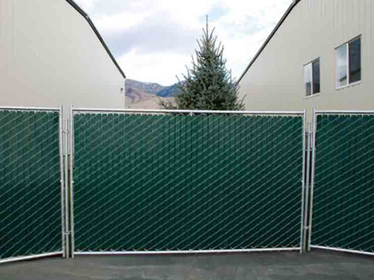 A chain link fence with green slats is sitting in front of a building.