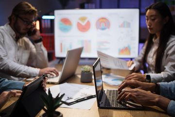 A Group of People Are Sitting at a Table Using Laptops