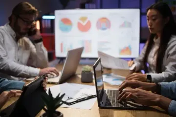 Team using laptops and charts to plan supply chain strategies for FMCG success