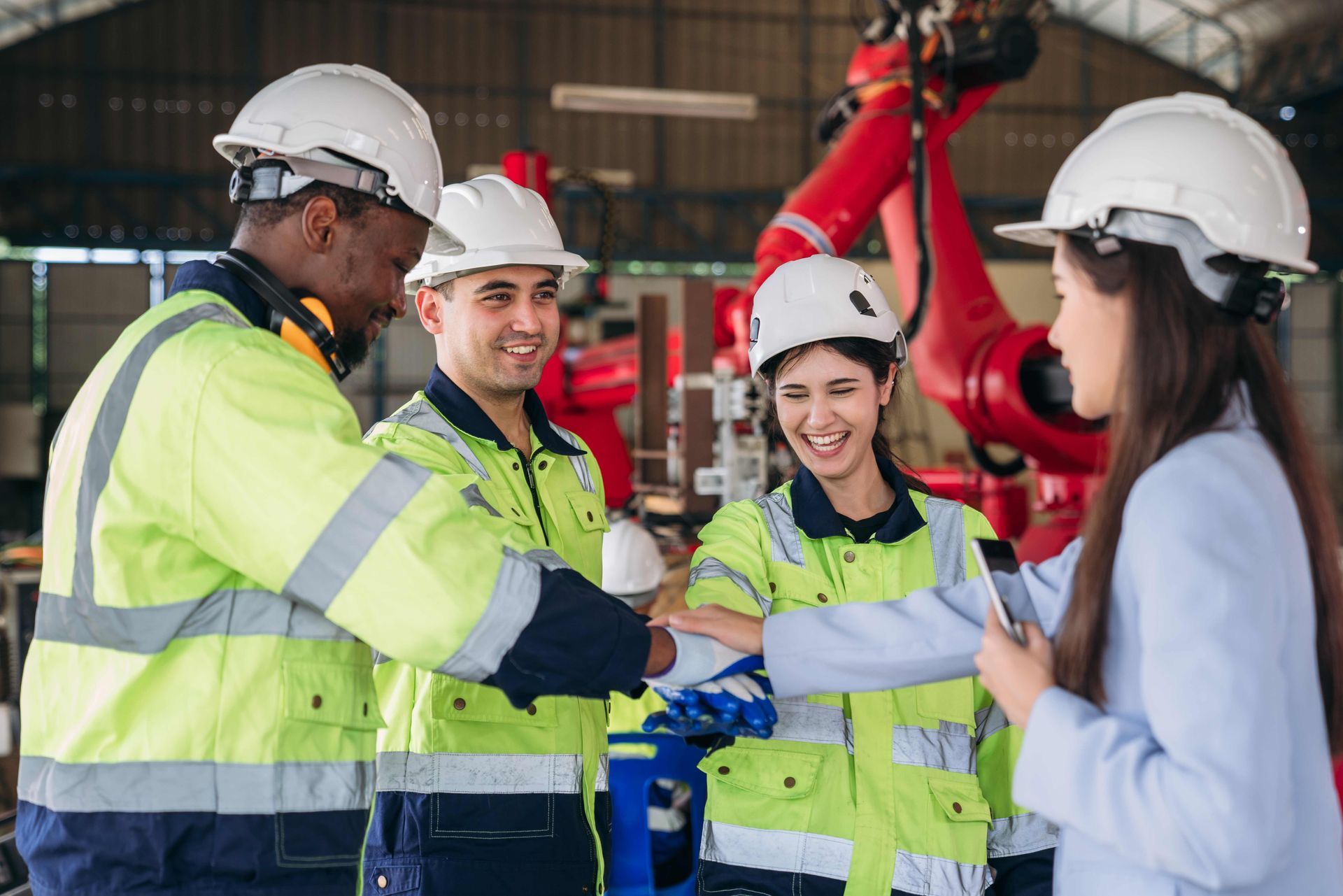 A Group Of Construction Workers Are Shaking Hands In A Factory.
