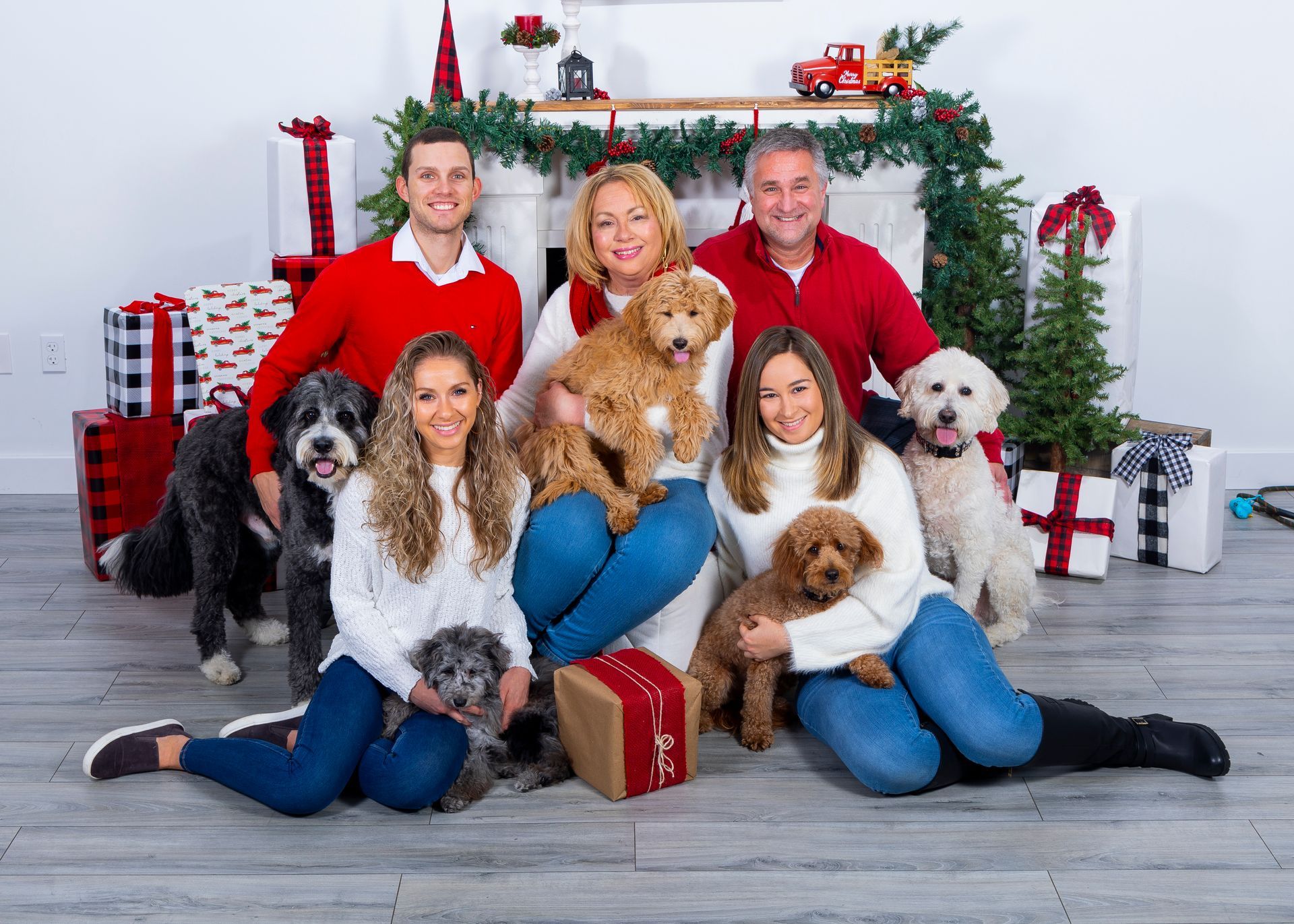 Family and dogs posed by a decorated Christmas fireplace with wrapped gifts