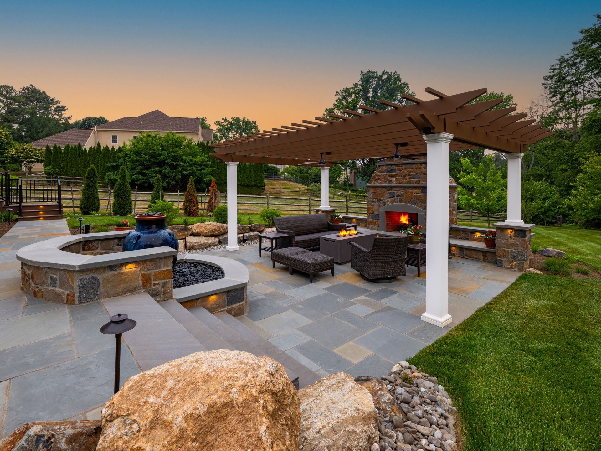 Backyard patio with pergola, fire pit, stone seating, and sunset mountain view