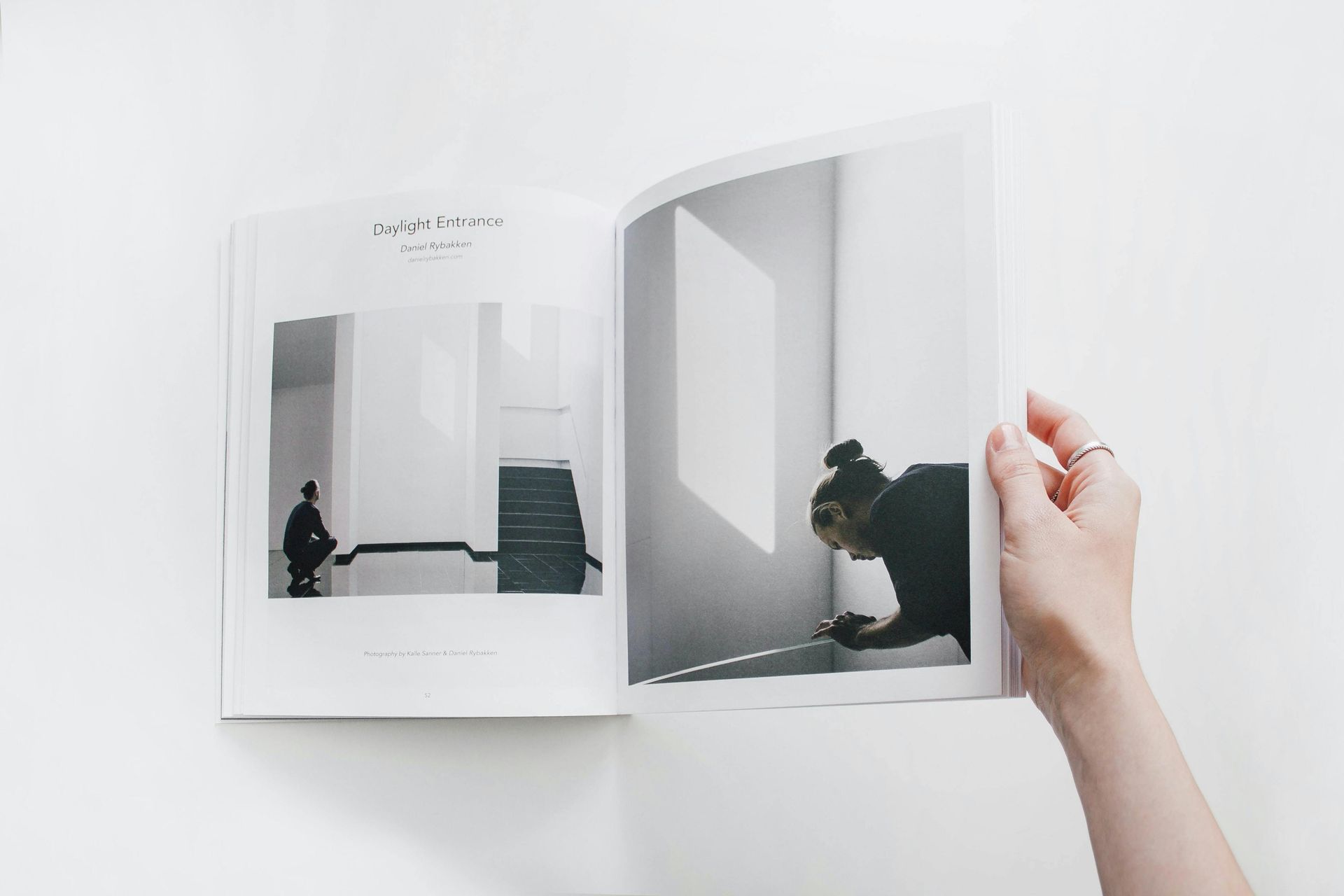Hand holding open a book with minimalist black-and-white interior illustrations of a cat near a doorway.