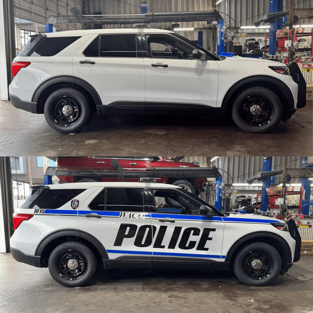 Two white Ford Explorer police SUVs, one plain, one with police markings, inside a shop. | Auto Design Specialty of Waco