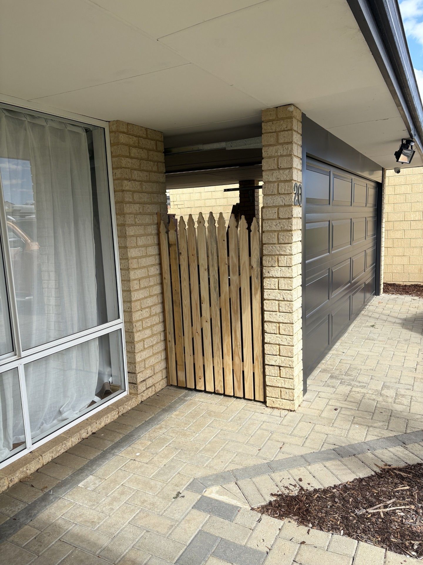 A person wearing yellow ear protection marks a wood board with a pencil and metal ruler on a table saw.