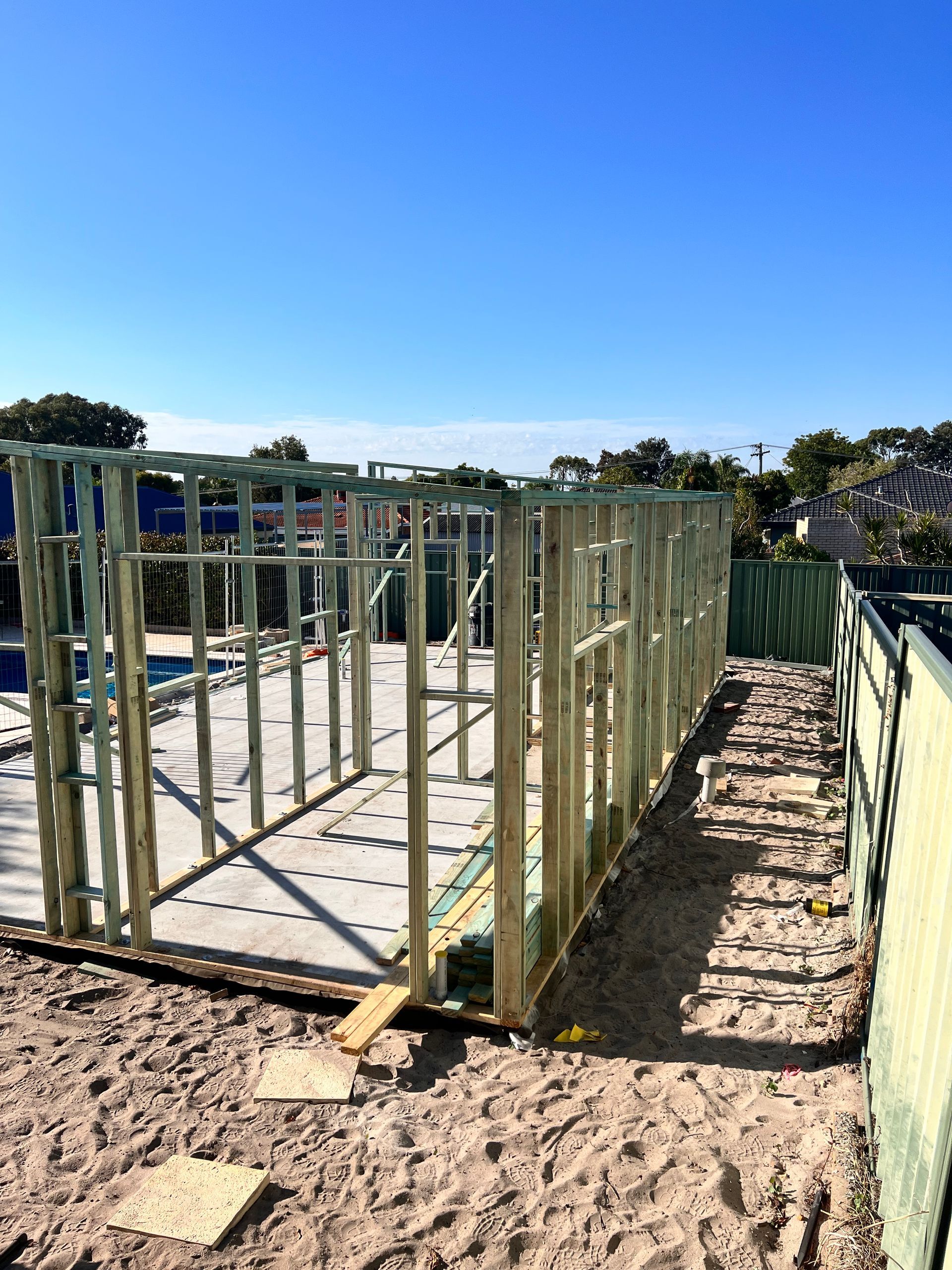 A person in blue work overalls installing wooden kitchen cabinet doors.