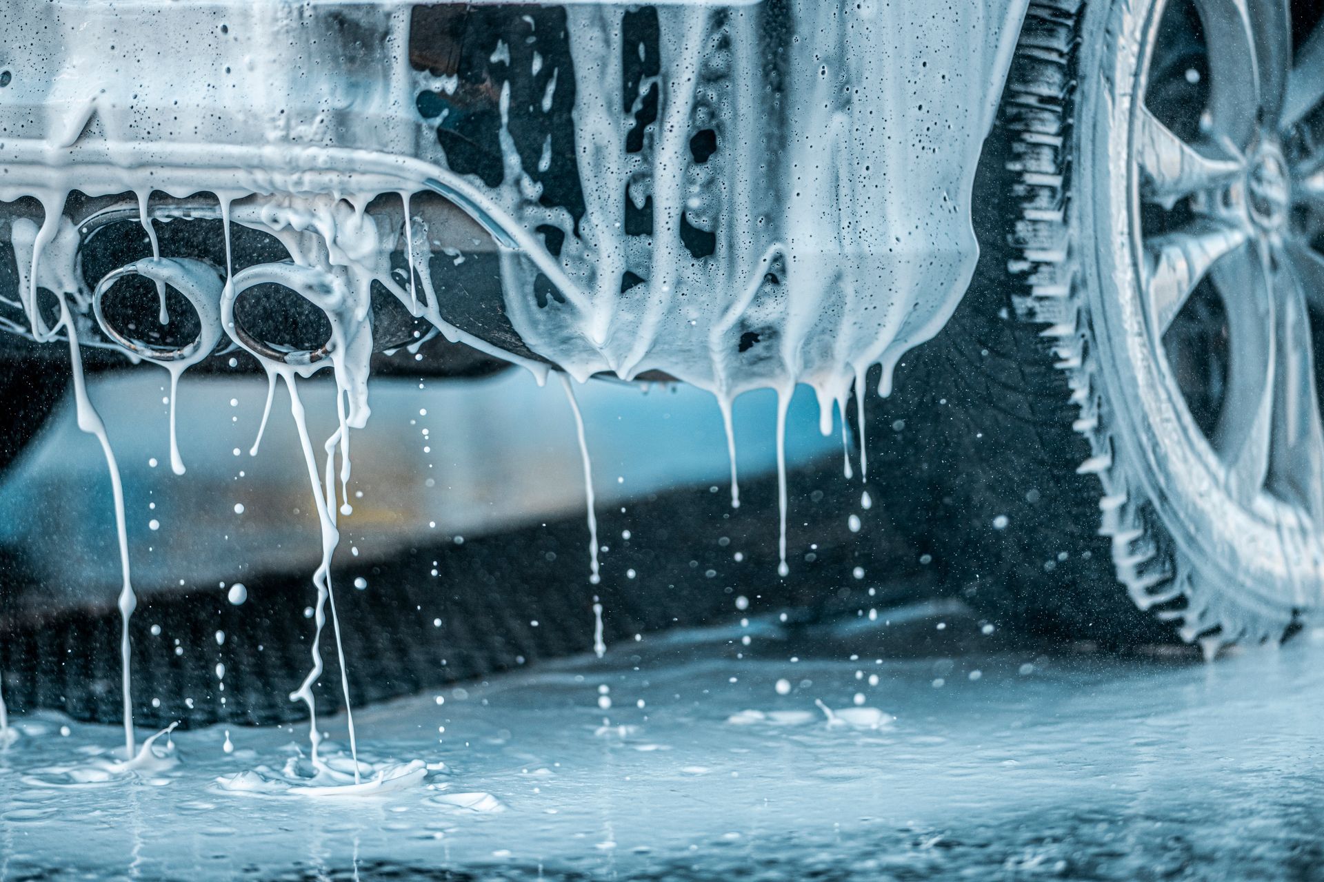 Thick foam soap dripping from rear bumper and dual exhaust during exterior car wash at Supreme Car Care in Old Bridge, NJ